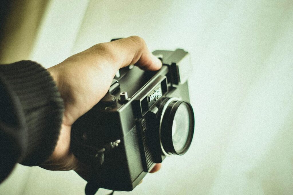 Close-up of a person holding a vintage film camera, emphasizing its retro style.